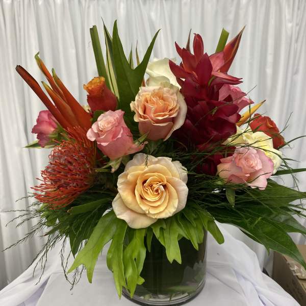 Mixed tropical bouquet with roses in a glass vase