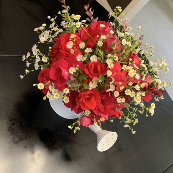 Red rose bouquet with small white daisy-like flowers in a white holder