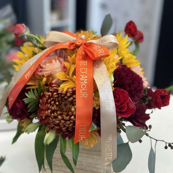 Bouquet of sunflowers, roses, and chrysanthemums with ribbon on a box