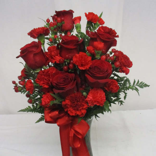 Red roses and carnations in a glass vase with a red ribbon
