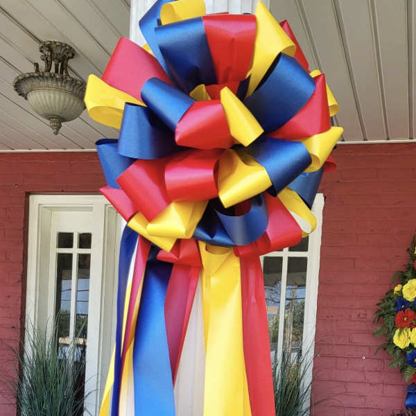 Large decorative ribbon bow in red, blue, and yellow hanging on a doorway