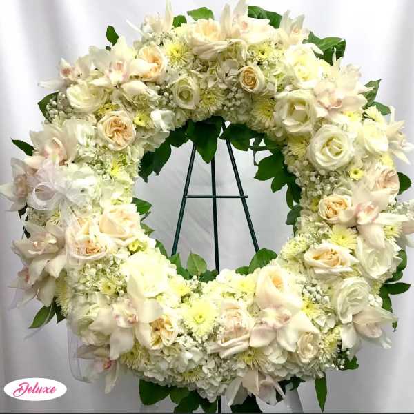 Creamy white floral wreath with roses and orchids on a stand