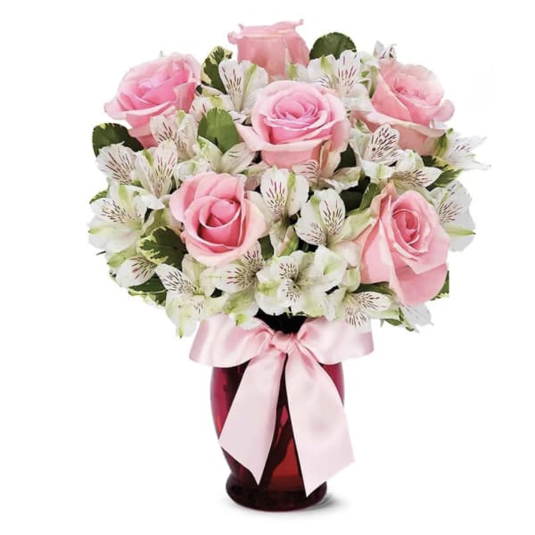 Pink roses and white alstroemeria in a red vase with a pink ribbon