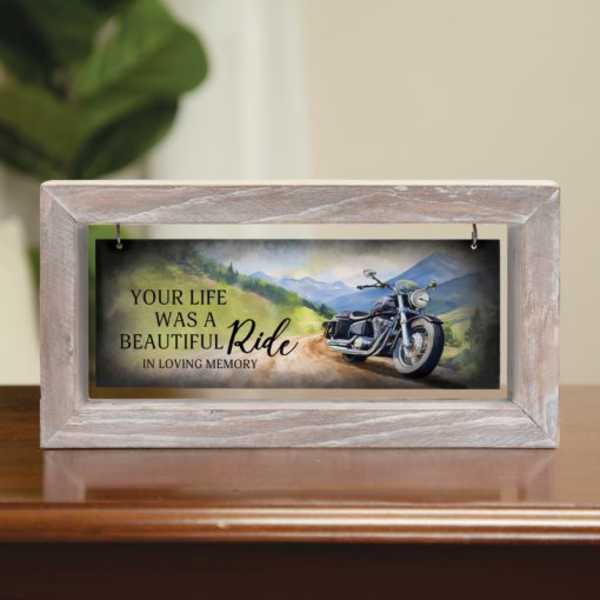 Memorial plaque in a light wood frame with a motorcycle scene