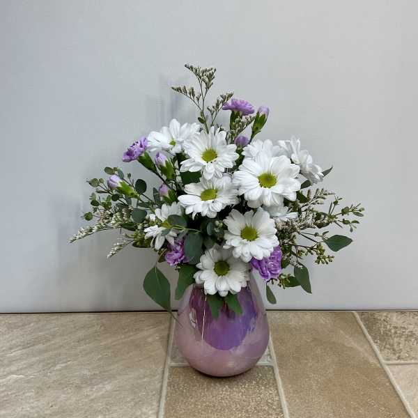 White daisies and purple blooms in a purple glass vase