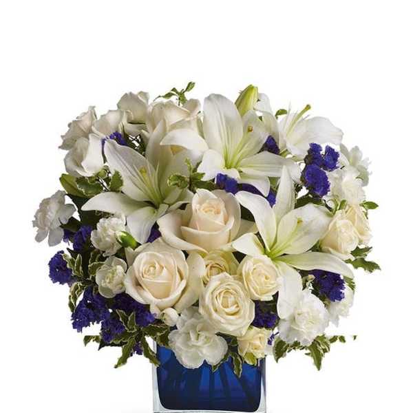 White lilies and cream roses arranged in a blue glass vase