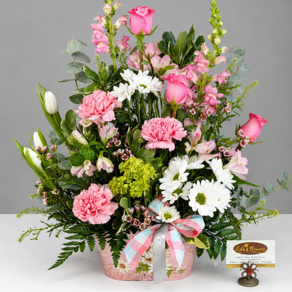 Pink and white mixed flower arrangement in a decorated basket with ribbon