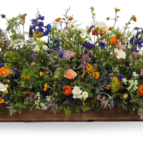Mixed bouquet of colorful flowers arranged in a low wooden container