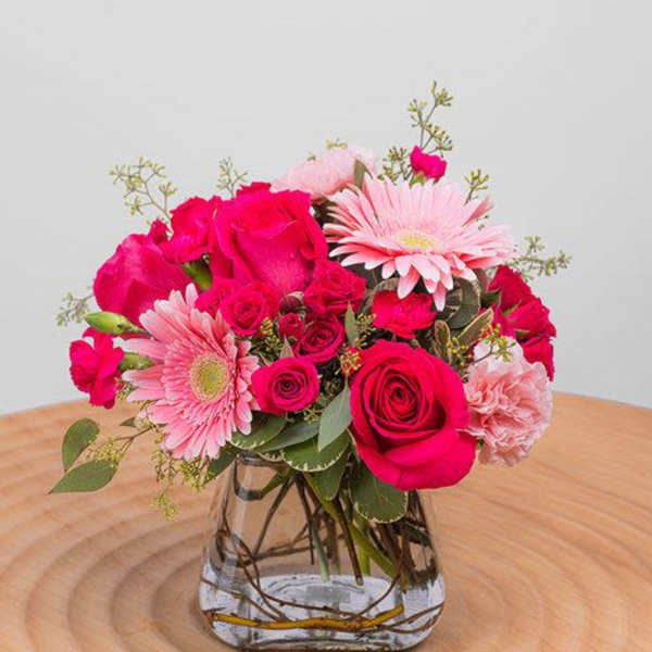 Pink roses and gerbera daisies arranged in a clear glass vase
