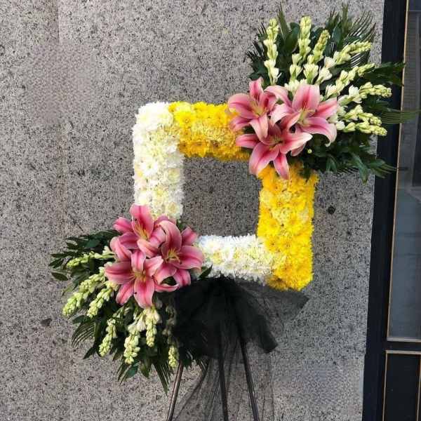 Floral standing wreath with pink lilies, white and yellow flowers on an easel