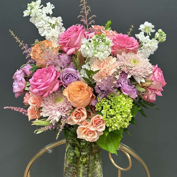 Mixed pink, peach, and white flowers in a clear glass vase