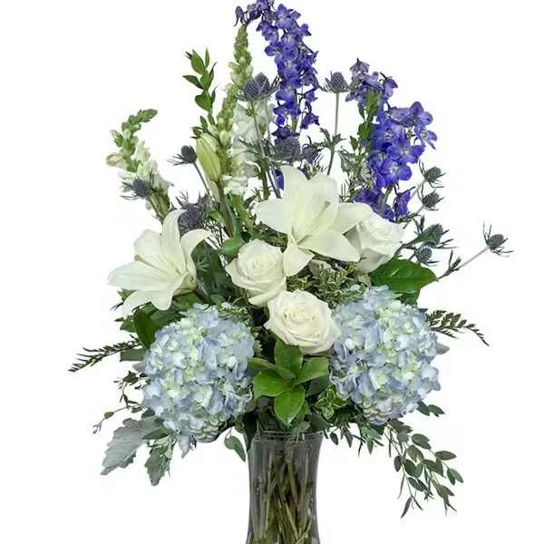 Blue hydrangeas, white lilies, and roses in a glass vase