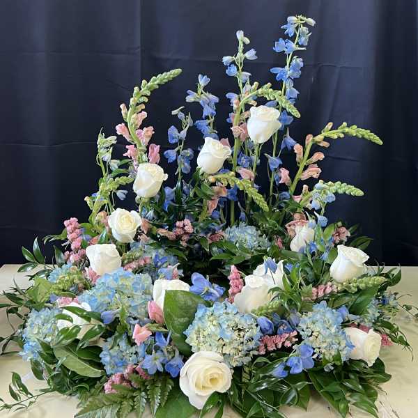 Large floral arrangement with white roses, blue blooms, and pink accents