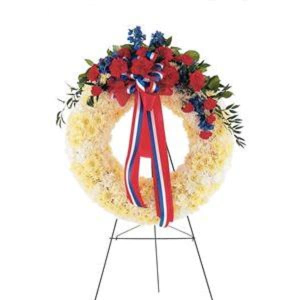 Red, white, and blue floral wreath on a metal stand with ribbon