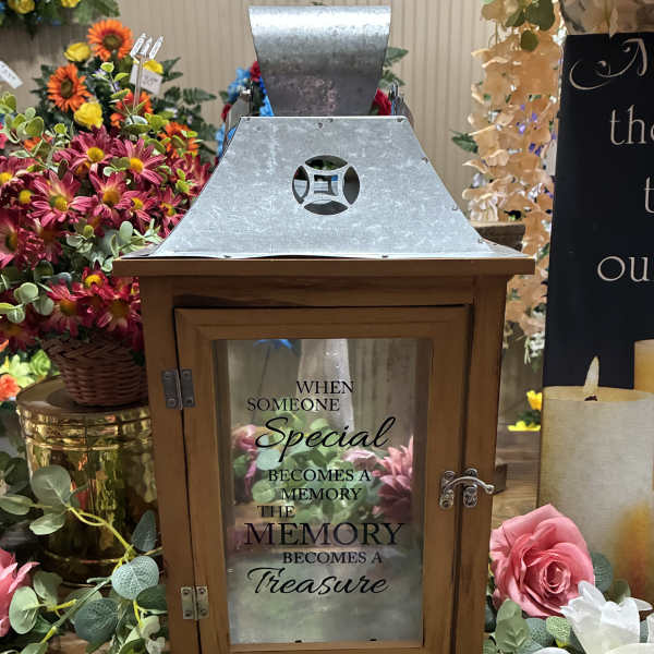 Wooden memorial lantern surrounded by pink and white flowers