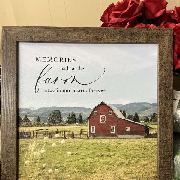 Framed farm sign with a red barn and red roses behind it
