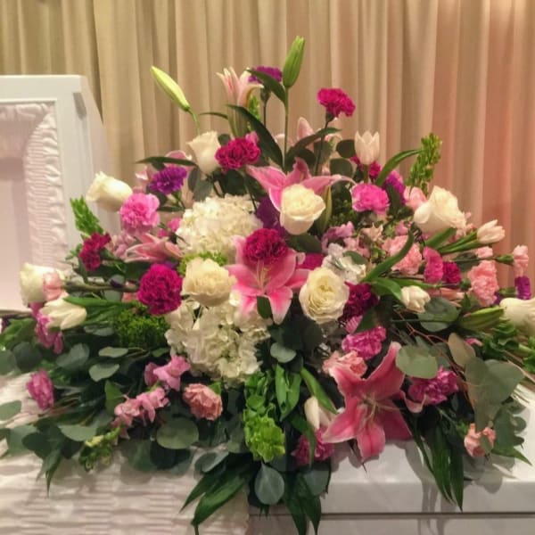 Large pink and white floral arrangement with lilies and roses on a table