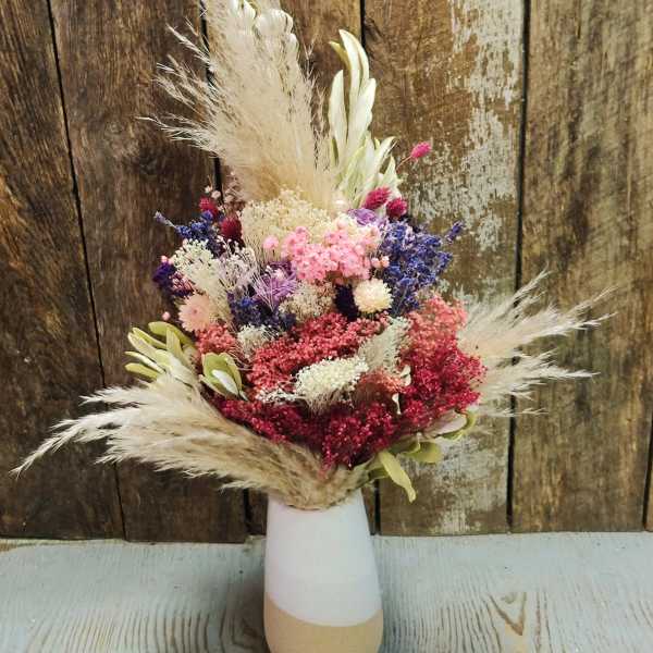 Dried flower arrangement in a white and tan vase