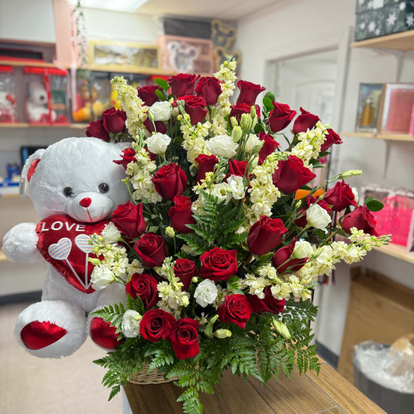 Red and white rose arrangement with a teddy bear holding a heart