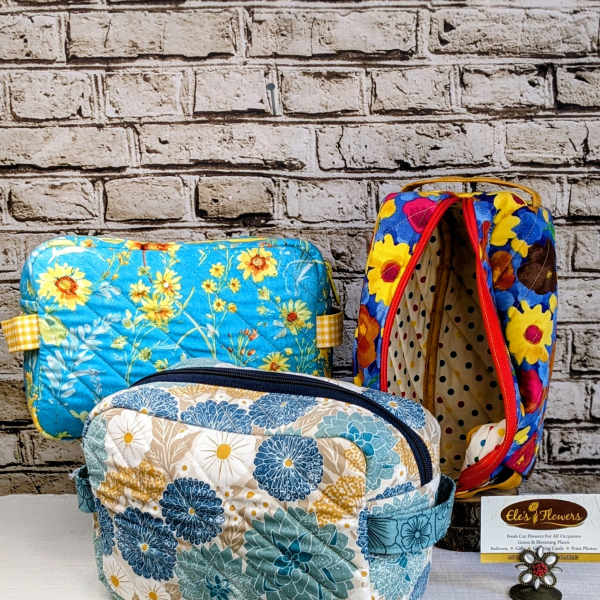 Three floral-patterned quilted zip pouches on a table