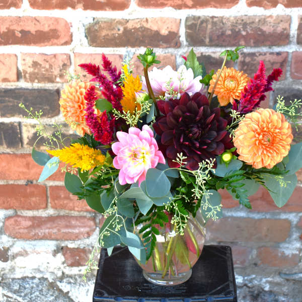 Mixed bouquet of dahlias and colorful filler flowers in a clear glass vase