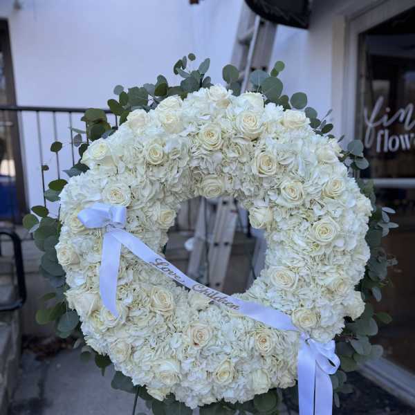 White floral wreath on an easel with a ribbon
