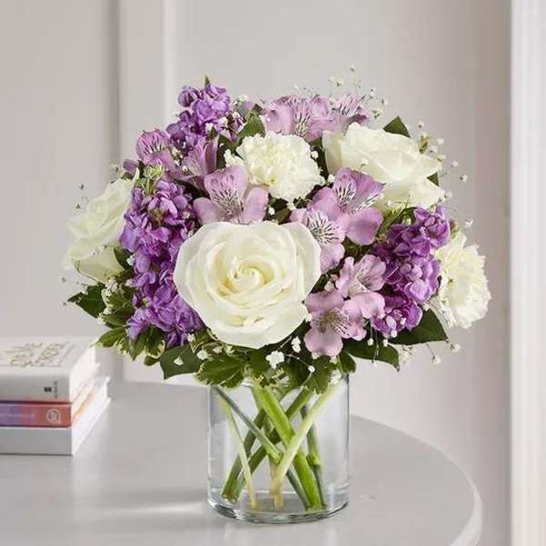 Bouquet of white and purple flowers in a clear glass vase