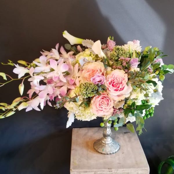 Pink roses and pale orchids arranged in a silver vase