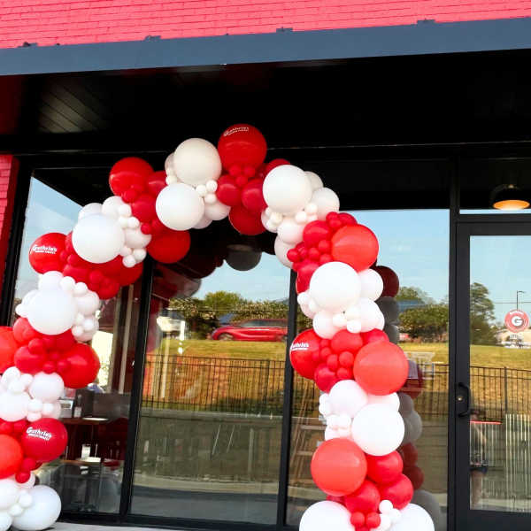 Red and white balloon arch outside a Guthrie's Chicken Fingers storefront
