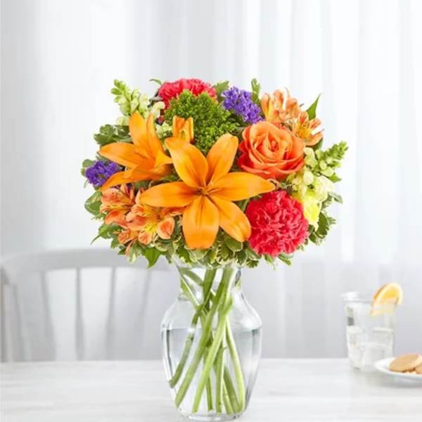 Orange and pink mixed bouquet in a clear glass vase