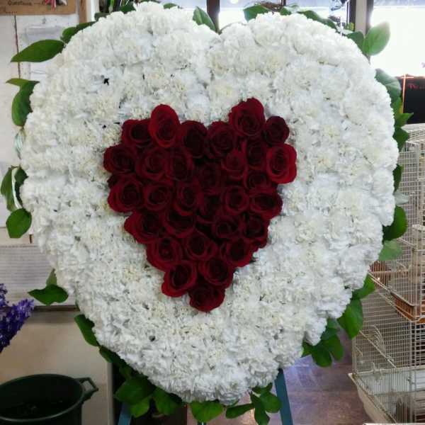 Heart-shaped floral tribute with red roses and white flowers