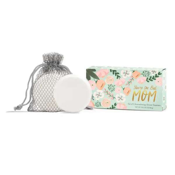 A mesh bag with a white shower steamer beside a floral gift box.