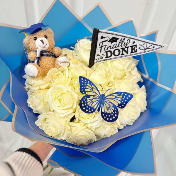 Bouquet of white roses with a teddy bear and graduation decorations