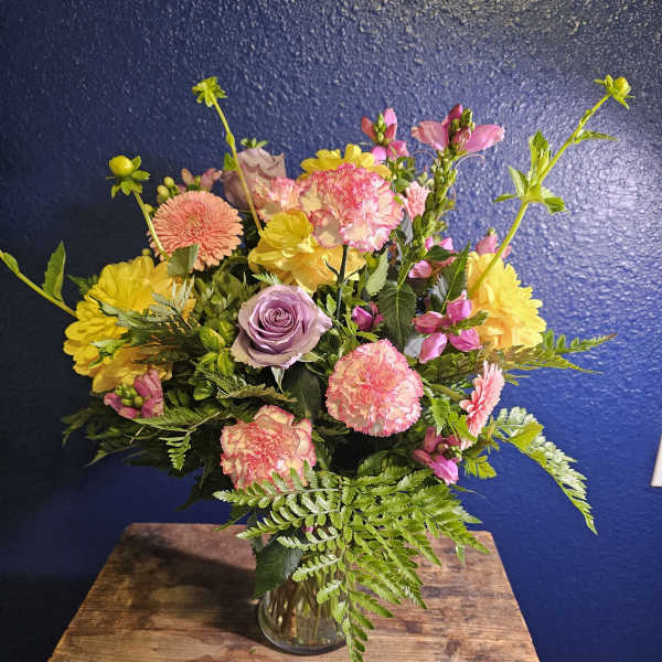Mixed bouquet in a clear glass vase with pink, yellow, and lavender blooms
