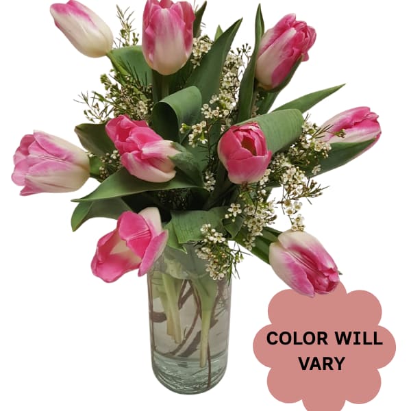 Pink tulips arranged in a clear glass vase with small white filler flowers