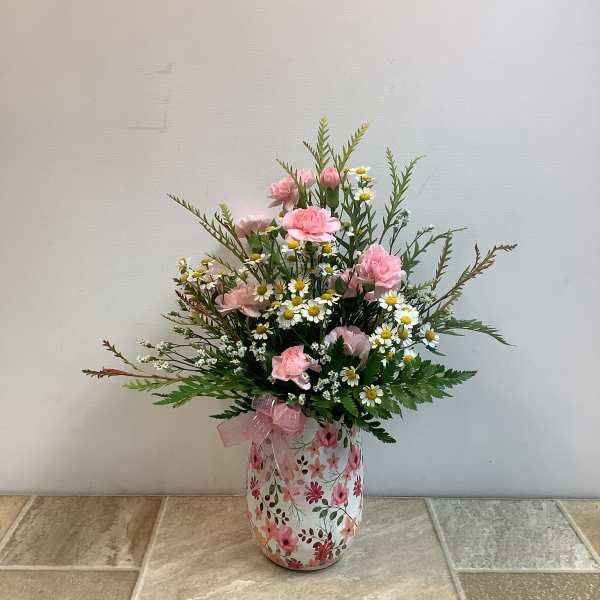 Pink carnations and small white daisies in a floral vase with a pink ribbon