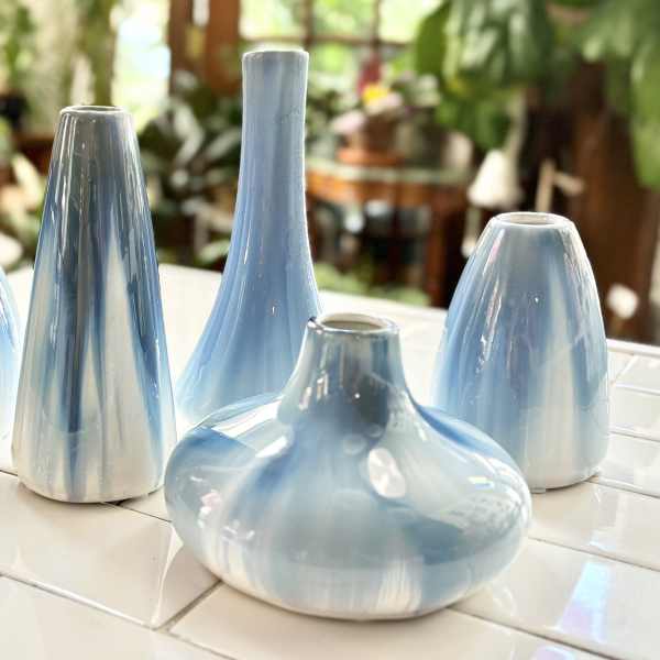 Five light blue ceramic vases on a tiled surface