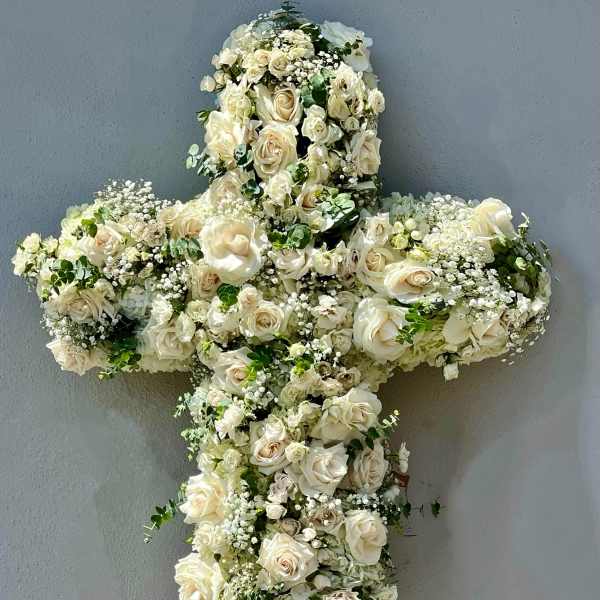 White floral cross arrangement on an easel