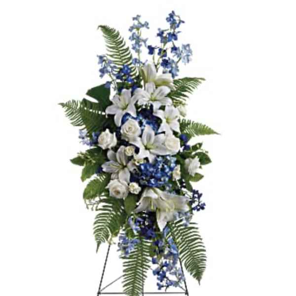 Standing floral spray with white lilies and blue flowers on an easel