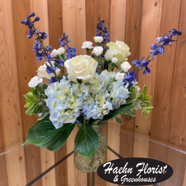 White roses and blue hydrangeas in a glass vase