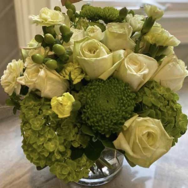 Cream roses and green hydrangeas arranged in a clear glass vase