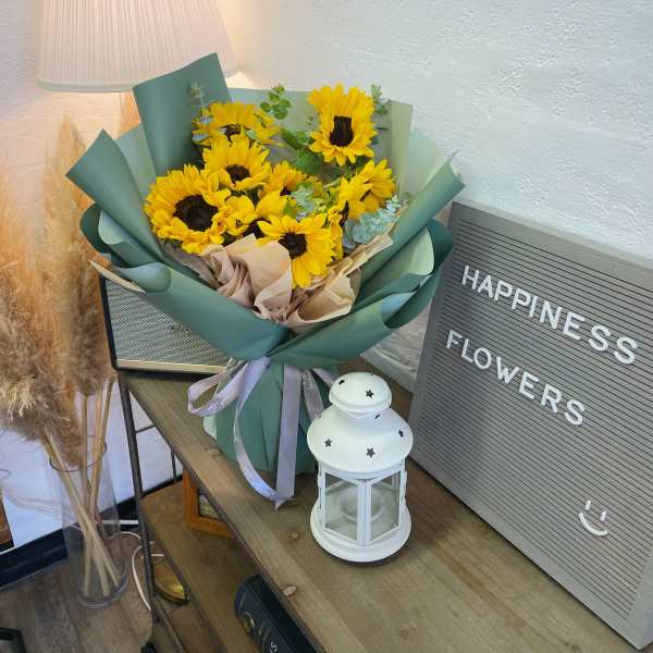 Bouquet of yellow sunflowers wrapped in green paper