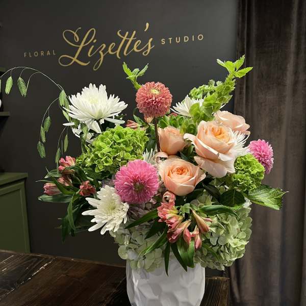 Mixed bouquet of peach roses, pink dahlias, and white chrysanthemums in a white vase