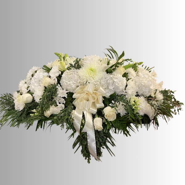 White floral casket spray with a cream ribbon bow