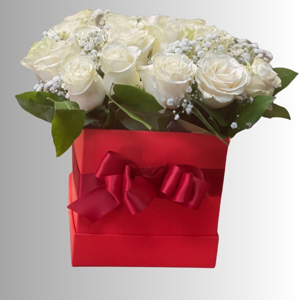 White roses in a red gift box with a ribbon bow