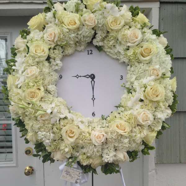 Large white floral wreath on a stand with cream roses and hydrangeas