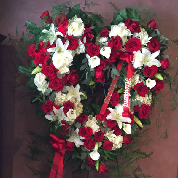 Heart-shaped wreath of red and white flowers with red ribbons