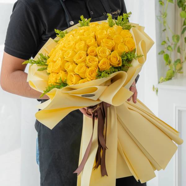 Bouquet of yellow roses wrapped in cream paper with brown ribbons