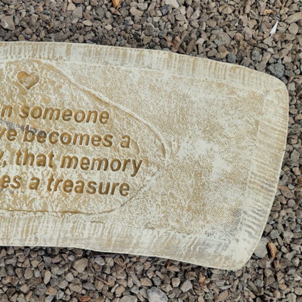 Memorial stone with an engraved quote on a gravel surface