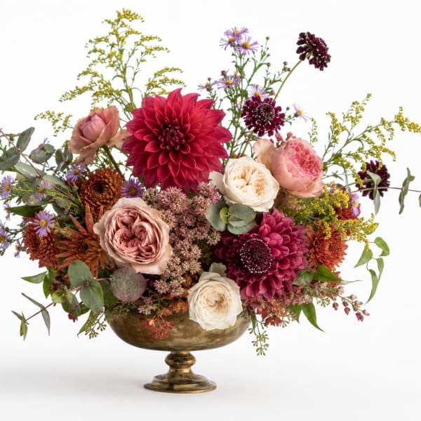 Mixed bouquet of pink, burgundy, and white flowers in a gold pedestal bowl
